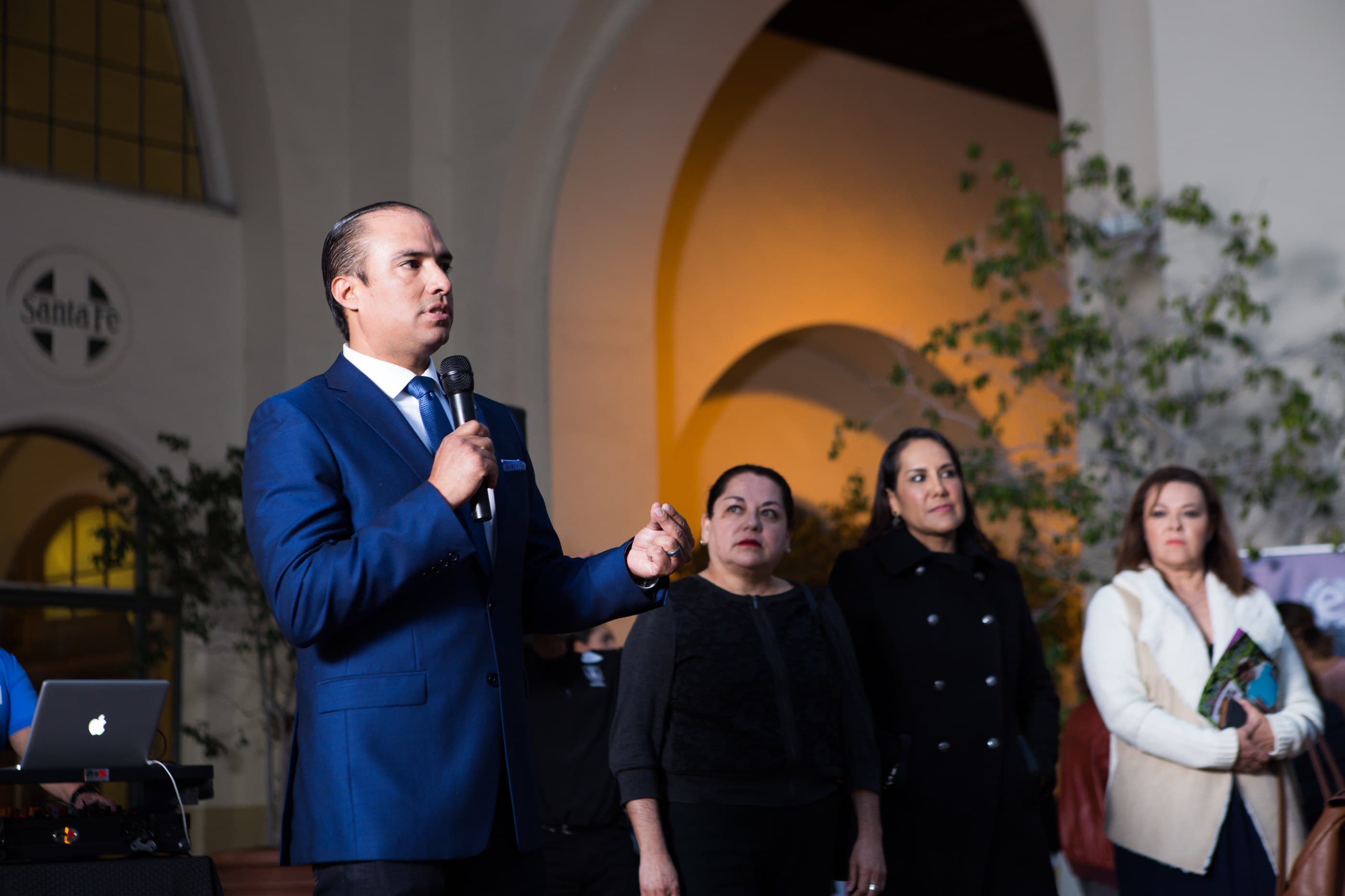 Tayde Aburto hablando ante una sala de dueños de negocio en un evento nocturno