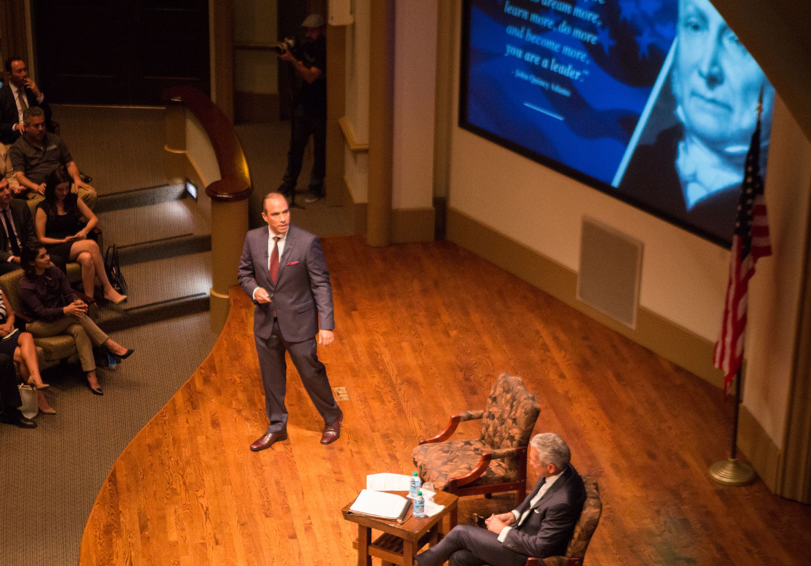 Tayde Aburto presenting on stage to a full auditorium of business owners