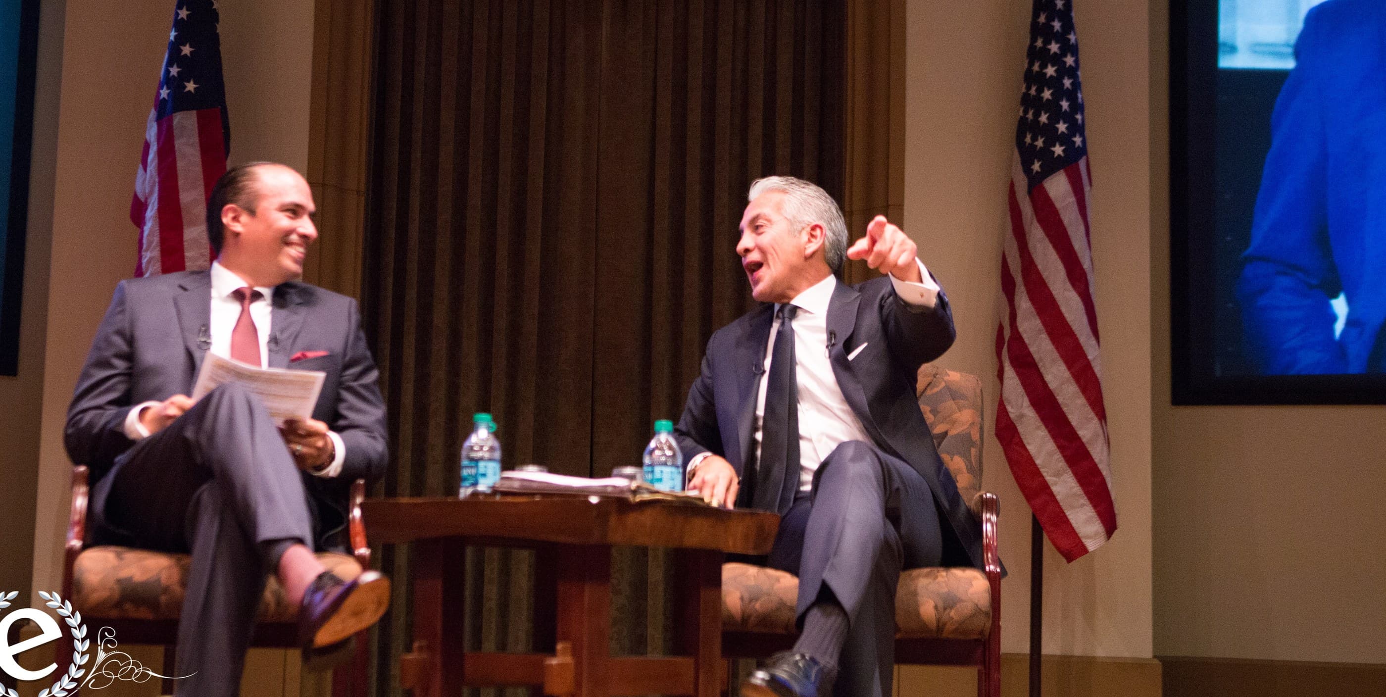 Tayde Aburto seated on stage in a fireside conversation, listening with notes in hand while the other participant speaks