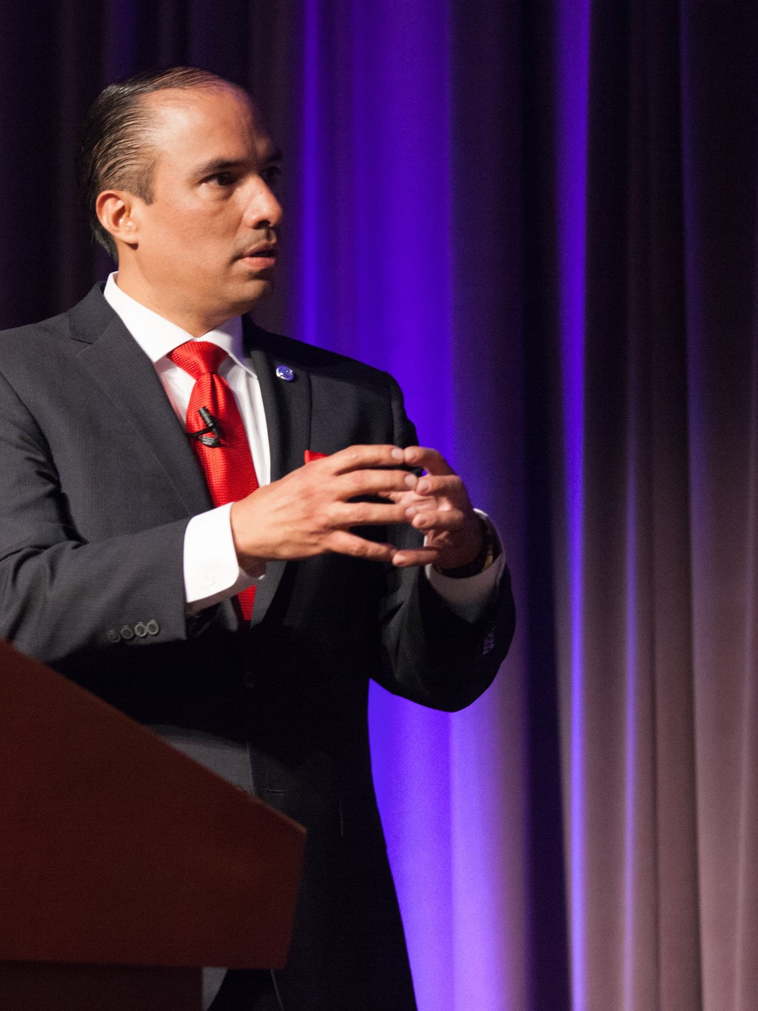 Tayde Aburto speaking on stage, hands mid-gesture as he explains an idea to an audience